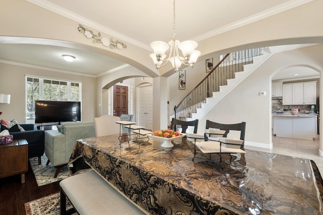 25611 Kearsley Dr, Katy, TX 77494 - dining area featuring arched walkways, crown molding, a chandelier, stairs, and light wood-type flooring