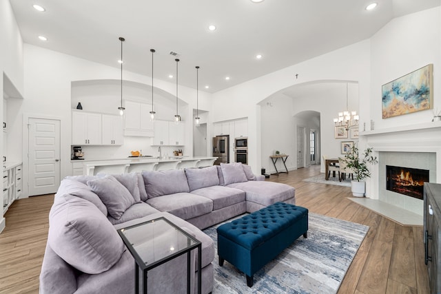 3019 Bluestem Rd, Katy, TX 77493 - living room featuring high vaulted ceiling, arched walkways, recessed lighting, light wood-type flooring, and a chandelier