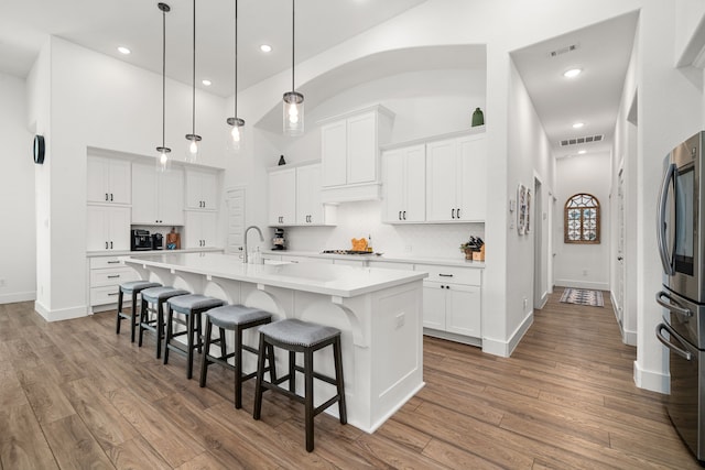 3019 Bluestem Rd, Katy, TX 77493 - kitchen with smart refrigerator, light countertops, a kitchen bar, wood finished floors, and decorative backsplash