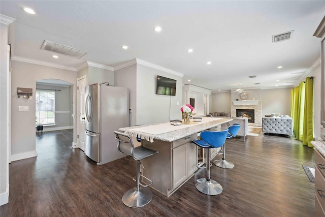 6319 Founding Dr, Katy, TX 77449 - kitchen with freestanding refrigerator, dark wood-style floors, a kitchen breakfast bar, arched walkways, and recessed lighting