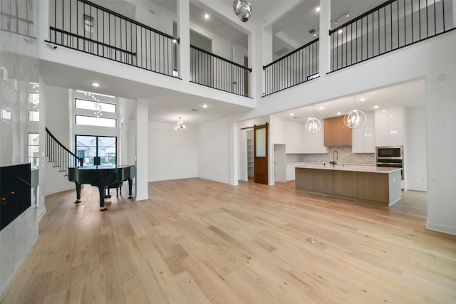 29602 Beech Tree Bnd, Fulshear, TX 77494 - unfurnished living room with a high ceiling, light wood finished floors, a barn door, recessed lighting, and a chandelier