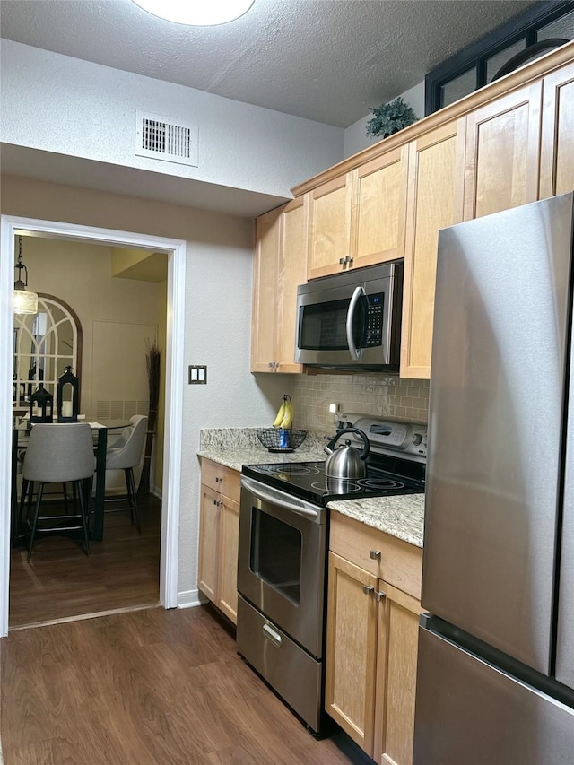 2255 Braeswood Park Dr Unit 145, Houston, TX 77030 - kitchen featuring appliances with stainless steel finishes, light brown cabinets, dark wood-style floors, tasteful backsplash, and a textured ceiling