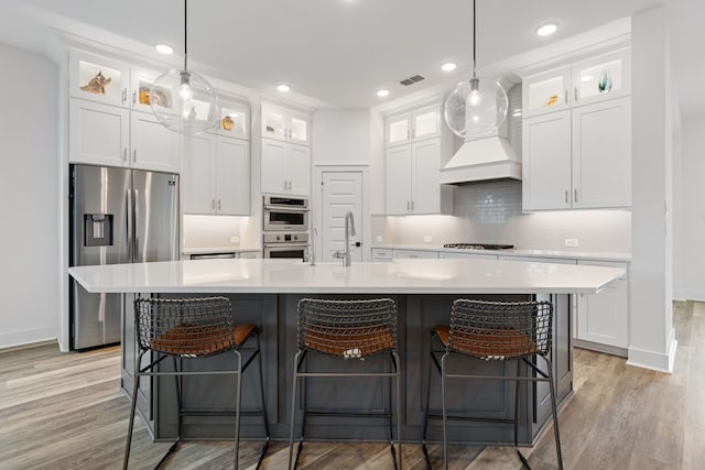 18615 Parkland Xing, Cypress, TX 77433 - kitchen with appliances with stainless steel finishes, custom range hood, light wood finished floors, white cabinetry, and recessed lighting