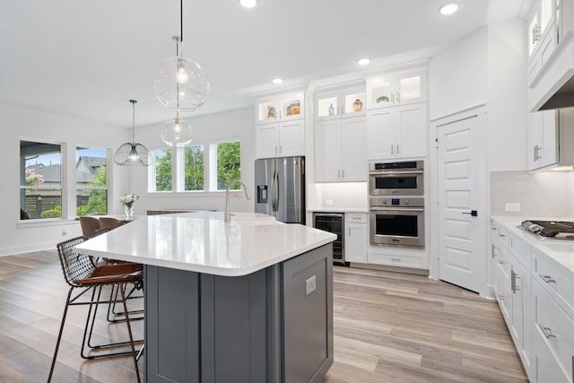 18615 Parkland Xing, Cypress, TX 77433 - kitchen featuring wine cooler, appliances with stainless steel finishes, light countertops, a breakfast bar, and light wood-type flooring