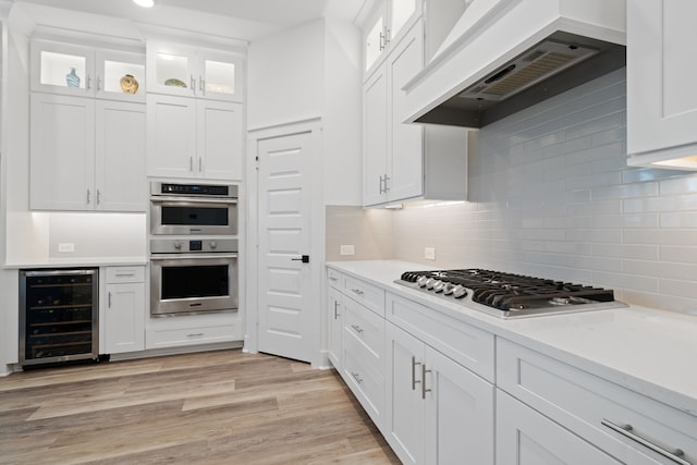 18615 Parkland Xing, Cypress, TX 77433 - kitchen featuring wine cooler, stainless steel appliances, range hood, white cabinetry, and light countertops