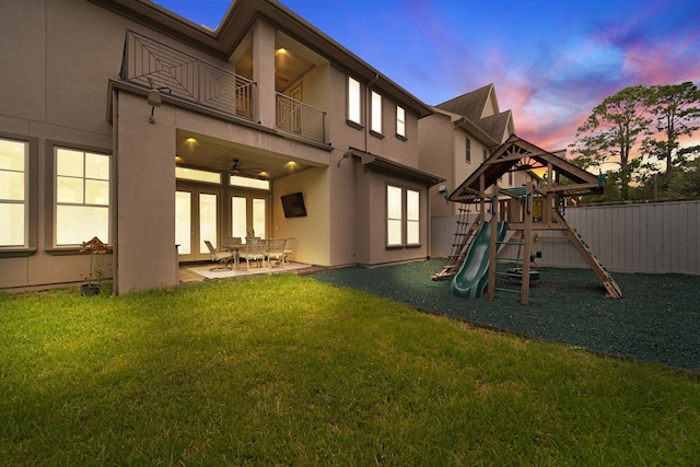 1302 Westview Garden Ct, Houston, TX 77055 - back of property at dusk with a balcony, stucco siding, a playground, a patio, and ceiling fan