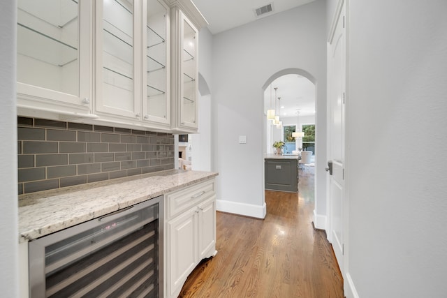 1302 Westview Garden Ct, Houston, TX 77055 - bar featuring wine cooler, wood finished floors, tasteful backsplash, and arched walkways
