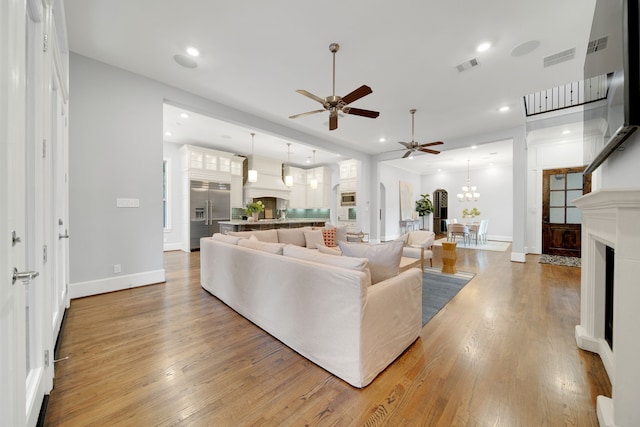 1302 Westview Garden Ct, Houston, TX 77055 - living room featuring a ceiling fan, light wood finished floors, recessed lighting, a chandelier, and a fireplace