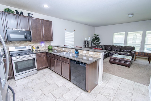 8222 Pastel Dawn Trce, Houston, TX 77049 - kitchen with black appliances, a peninsula, open floor plan, dark stone countertops, and decorative backsplash