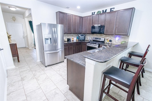 8222 Pastel Dawn Trce, Houston, TX 77049 - kitchen featuring stainless steel appliances, decorative backsplash, a breakfast bar, dark stone countertops, and dark brown cabinetry