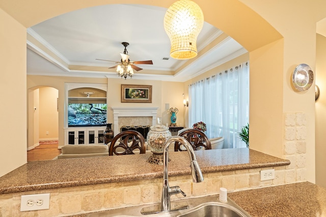 16018 Lower Lake Dr, Cypress, TX 77433 - kitchen featuring arched walkways, ceiling fan, crown molding, a raised ceiling, and a fireplace