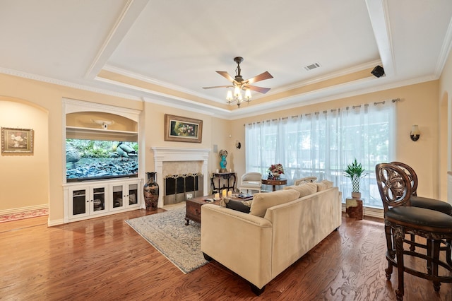 16018 Lower Lake Dr, Cypress, TX 77433 - living room with a raised ceiling, ceiling fan, dark wood-style flooring, ornamental molding, and a fireplace