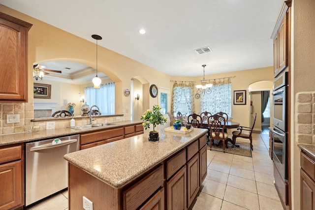 16018 Lower Lake Dr, Cypress, TX 77433 - kitchen featuring stainless steel appliances, arched walkways, brown cabinetry, a center island, and a chandelier