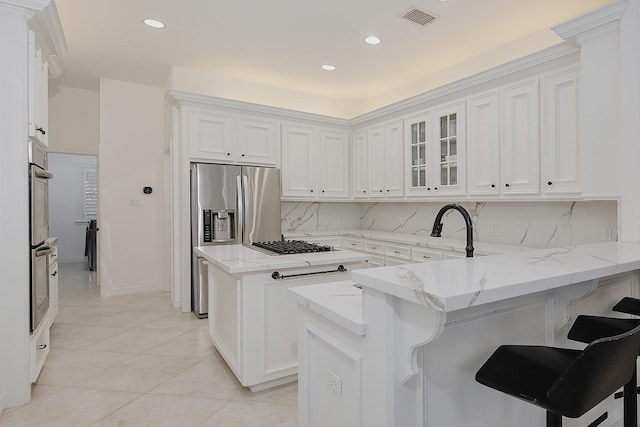 26 W Fairbranch Cir, The Woodlands, TX 77382 - kitchen with stainless steel appliances, a peninsula, white cabinets, a kitchen island, and glass insert cabinets