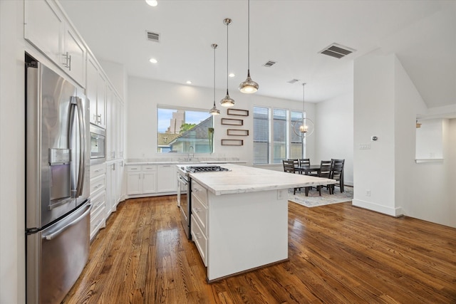 1408 Ruthven St, Houston, TX 77019 - kitchen featuring appliances with stainless steel finishes, a kitchen island, white cabinets, dark wood-style flooring, and light stone countertops