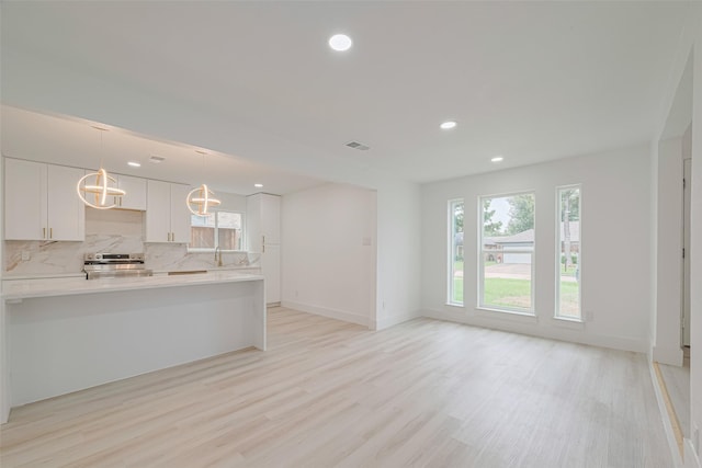 17802 Poppy Trails Ln, Houston, TX 77084 - kitchen featuring stainless steel range with electric stovetop, light countertops, light wood-style floors, white cabinetry, and recessed lighting