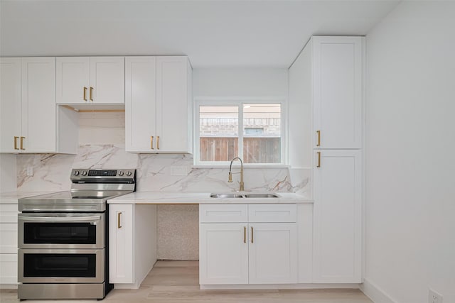 17802 Poppy Trails Ln, Houston, TX 77084 - kitchen with range with two ovens, light wood-type flooring, light countertops, white cabinetry, and tasteful backsplash