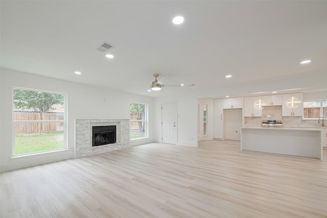17802 Poppy Trails Ln, Houston, TX 77084 - unfurnished living room with healthy amount of natural light, light wood-style flooring, recessed lighting, ceiling fan, and a stone fireplace