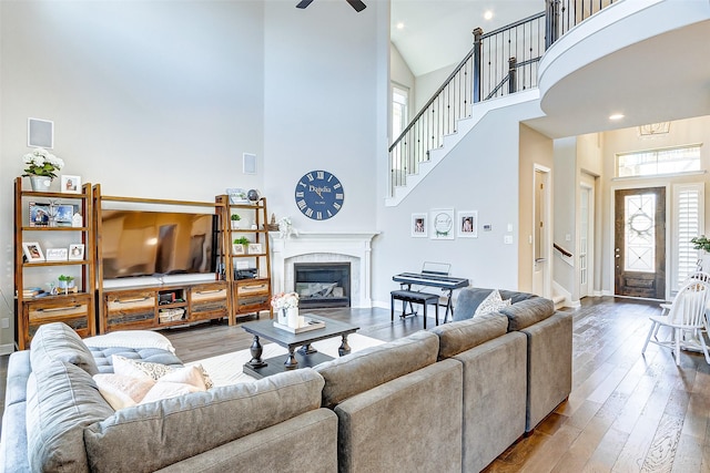 28606 Royal Pines Ct, Fulshear, TX 77441 - living room featuring a towering ceiling, stairway, hardwood / wood-style flooring, a high end fireplace, and ceiling fan