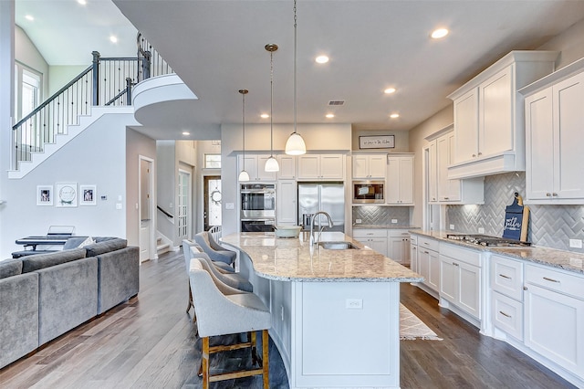 28606 Royal Pines Ct, Fulshear, TX 77441 - kitchen featuring built in appliances, dark wood finished floors, open floor plan, white cabinets, and backsplash