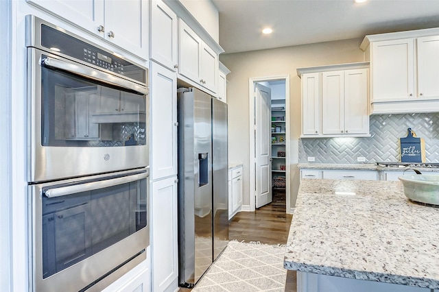 28606 Royal Pines Ct, Fulshear, TX 77441 - kitchen featuring appliances with stainless steel finishes, backsplash, white cabinetry, recessed lighting, and dark wood-style flooring