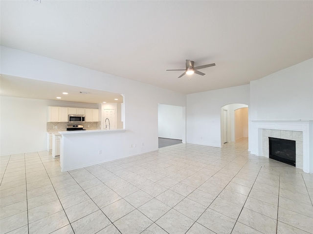 15311 Streetcar Ct, Cypress, TX 77429 - unfurnished living room featuring ceiling fan, light tile patterned flooring, recessed lighting, arched walkways, and a tiled fireplace