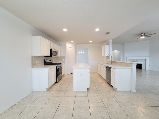15311 Streetcar Ct, Cypress, TX 77429 - kitchen featuring appliances with stainless steel finishes, a center island, backsplash, light tile patterned flooring, and light countertops