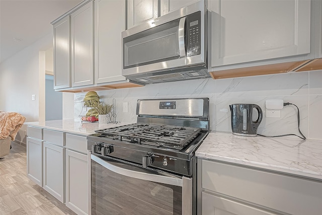1815 Sandy Trail Ln, Rosenberg, TX 77469 - kitchen with appliances with stainless steel finishes, decorative backsplash, light stone counters, and light wood-style flooring