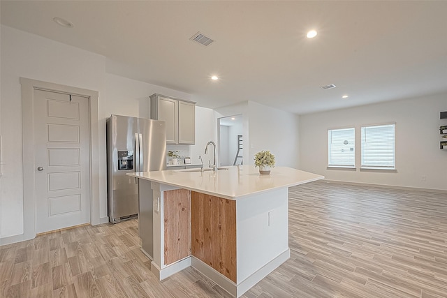 1815 Sandy Trail Ln, Rosenberg, TX 77469 - kitchen featuring stainless steel refrigerator with ice dispenser, light wood-style flooring, an island with sink, light countertops, and recessed lighting