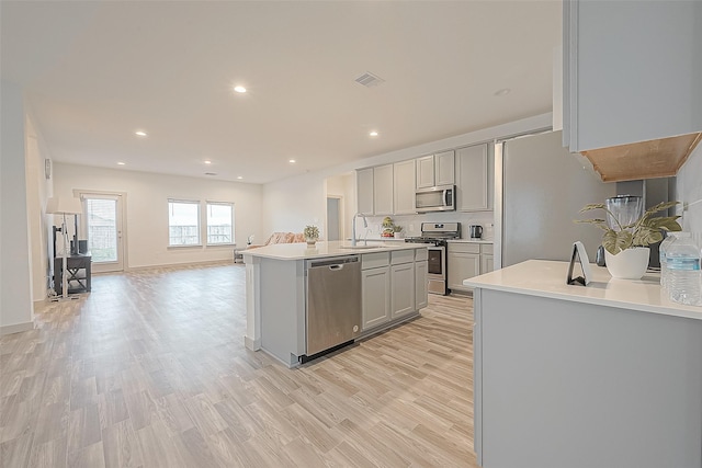 1815 Sandy Trail Ln, Rosenberg, TX 77469 - kitchen with stainless steel appliances, open floor plan, light countertops, light wood-style flooring, and gray cabinets