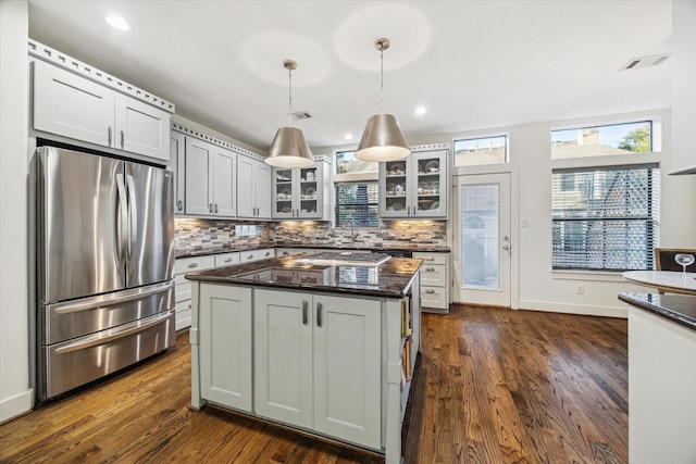 6410 Rodrigo St Unit B, Houston, TX 77007 - kitchen with stainless steel fridge, decorative backsplash, glass insert cabinets, dark wood-type flooring, and dark stone countertops