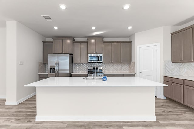 21521 Witham Promenade Ln, Magnolia, TX 77355 - kitchen with stainless steel appliances, a kitchen island with sink, decorative backsplash, light countertops, and recessed lighting