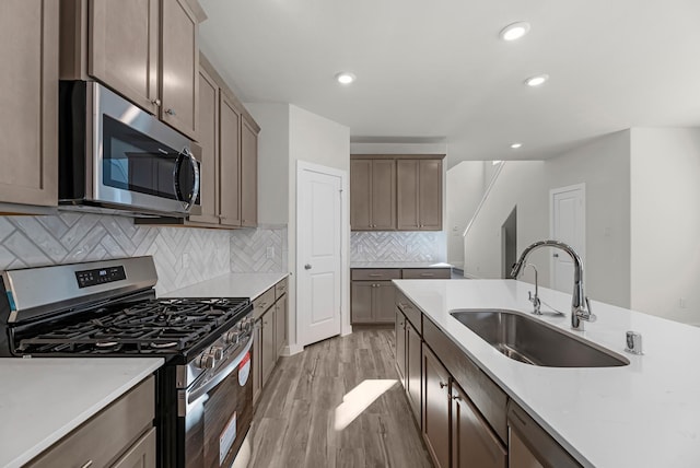 21521 Witham Promenade Ln, Magnolia, TX 77355 - kitchen with appliances with stainless steel finishes, light wood-style floors, backsplash, light countertops, and recessed lighting