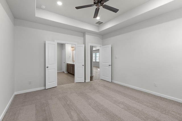 21521 Witham Promenade Ln, Magnolia, TX 77355 - unfurnished bedroom featuring light carpet, a tray ceiling, and connected bathroom