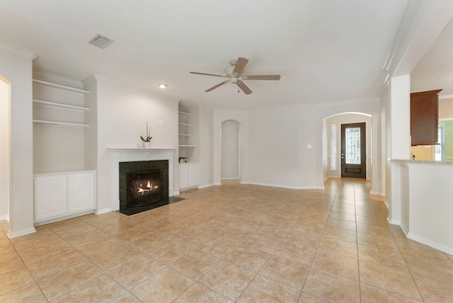 31 N Winterport Cir, The Woodlands, TX 77382 - unfurnished living room featuring arched walkways, built in shelves, a ceiling fan, light tile patterned flooring, and a fireplace with flush hearth