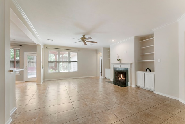 31 N Winterport Cir, The Woodlands, TX 77382 - unfurnished living room featuring light tile patterned flooring, ceiling fan, a premium fireplace, crown molding, and built in shelves