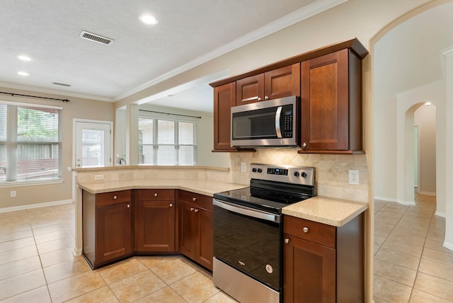 31 N Winterport Cir, The Woodlands, TX 77382 - kitchen featuring stainless steel appliances, arched walkways, light tile patterned flooring, a peninsula, and crown molding