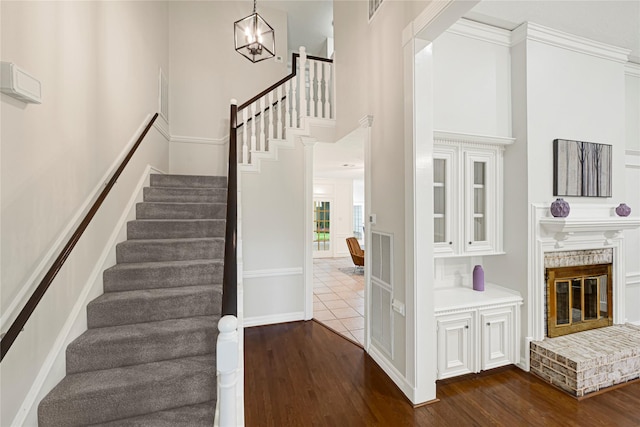 2814 Rustic Woods Dr, Houston, TX 77345 - staircase featuring wood finished floors, a towering ceiling, a chandelier, and a fireplace