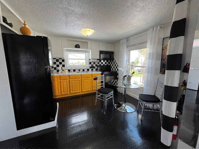 6625 Morris, Galveston, TX 77551 - kitchen with black appliances, healthy amount of natural light, tasteful backsplash, light countertops, and a textured ceiling