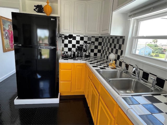 6625 Morris, Galveston, TX 77551 - kitchen featuring freestanding refrigerator, tile countertops, white cabinetry, and decorative backsplash