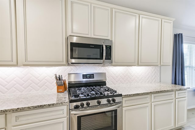 24218 Birchwood Creek Ct, Spring, TX 77389 - kitchen featuring stainless steel appliances, decorative backsplash, light stone countertops, and white cabinetry