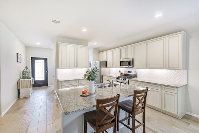 24218 Birchwood Creek Ct, Spring, TX 77389 - kitchen with stainless steel appliances, tasteful backsplash, light stone counters, a kitchen island with sink, and a kitchen breakfast bar