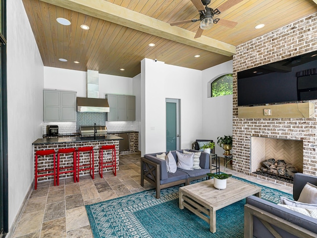 518 Hallie Dr, Houston, TX 77024 - living room with an outdoor brick fireplace, a ceiling fan, recessed lighting, a wooden ceiling with exposed beams, and stone finish flooring