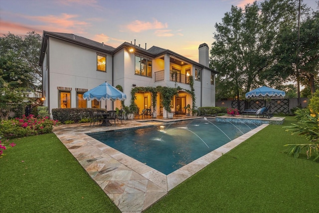 7614 Brykerwoods Dr, Houston, TX 77055 - back of property at dusk featuring a balcony, a patio area, an outdoor pool, and a chimney