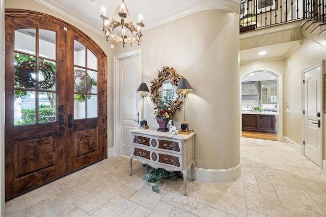 7614 Brykerwoods Dr, Houston, TX 77055 - entrance foyer featuring stone tile floors, arched walkways, ornamental molding, and a chandelier