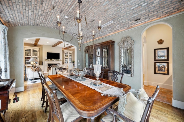 7614 Brykerwoods Dr, Houston, TX 77055 - dining area featuring arched walkways, brick ceiling, wood finished floors, a fireplace, and vaulted ceiling