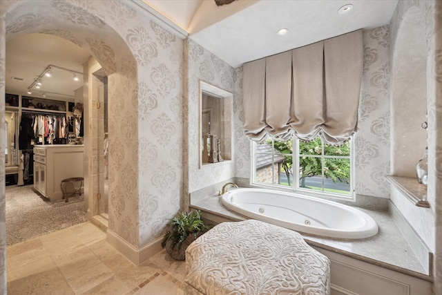 7614 Brykerwoods Dr, Houston, TX 77055 - bathroom featuring wallpapered walls, a jetted tub, a spacious closet, and track lighting