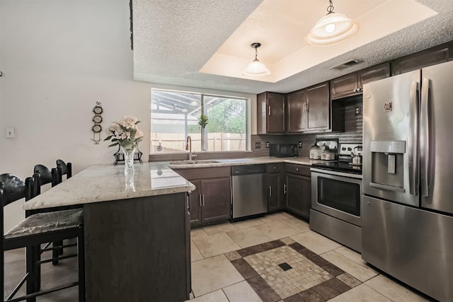 7642 Candlegreen Ln, Houston, TX 77071 - kitchen featuring stainless steel appliances, a breakfast bar area, a tray ceiling, a peninsula, and dark brown cabinetry