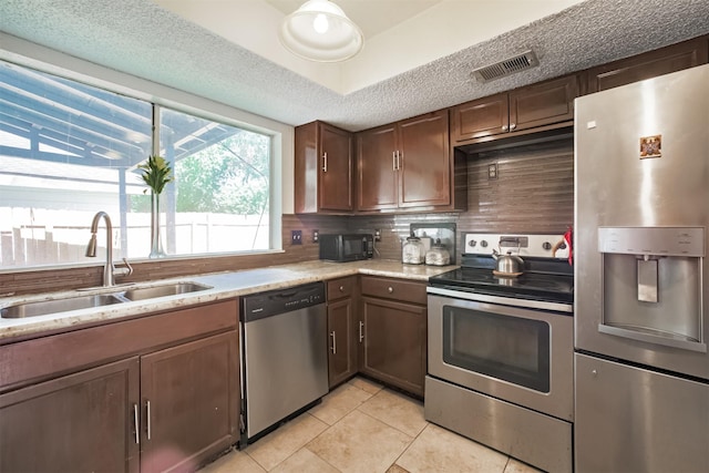 7642 Candlegreen Ln, Houston, TX 77071 - kitchen with appliances with stainless steel finishes, light tile patterned floors, tasteful backsplash, dark brown cabinets, and light stone countertops