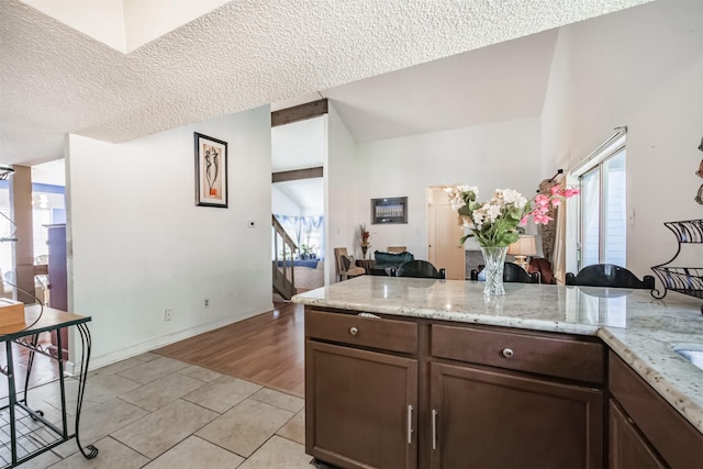7642 Candlegreen Ln, Houston, TX 77071 - kitchen with healthy amount of natural light, light tile patterned floors, a textured ceiling, lofted ceiling, and light stone counters